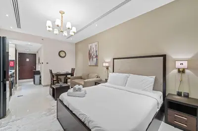 a bedroom with a large bed and a living room at Modern Studio at Elite Downtown Residence in Dubai