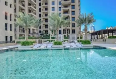 a large pool with chairs and palm trees and buildings at Chic Apartment with Balcony & Views in Dubai