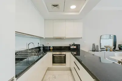 a kitchen with white cabinets and a counter top at RH-Luxury 1BR Apt in Al Habtoor City with beautiful Canal View in Dubai