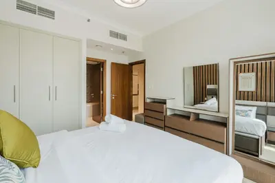 a bedroom with a large white bed and a mirror at RH-Luxury 1BR Apt in Al Habtoor City with beautiful Canal View in Dubai