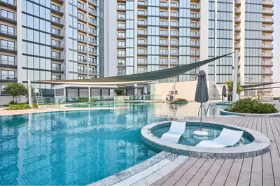a swimming pool with two chairs and a large building at STAY BY LATINEM Luxury 1BR Plus Study Holiday Home CB 1013 Near Burj Khalifa in Dubai