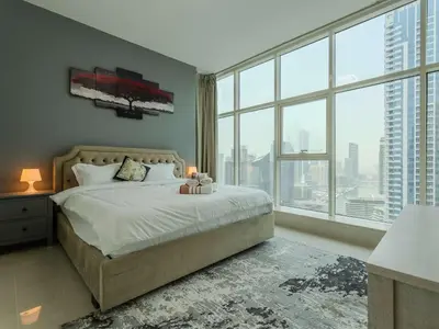 a bedroom with a bed and a large window at Continental Tower Stylish 2BR and Private Hot Tub in Dubai