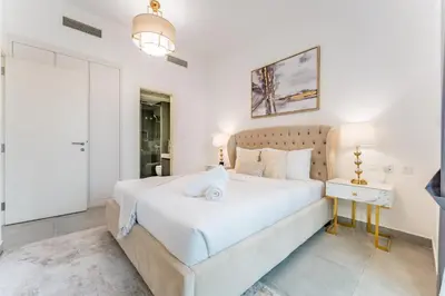 a bedroom with a large white bed and a table at Near Circle Mall And Parks, Easy Access to Al Khail Road And Close to RTA Bus Stop, Lucky Residences, JVC by Deluxe Holiday Homes in Dubai