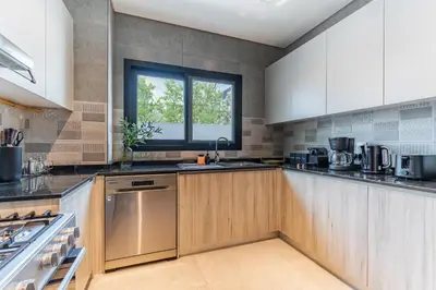 a large kitchen with wooden cabinets and a window at Private Pool Paradise Villa! Dubai Mall in a Flash! Complimentary Full Mid-Stay Refresh for 1 week stay in Dubai