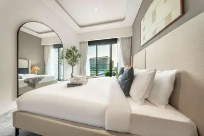 a large white bed in a room with a mirror at AirDXB - Meydan Apartment sleeps 4 in Great Location in Dubai