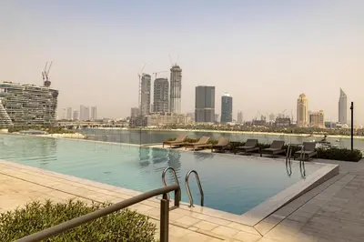 a swimming pool with chairs and a city skyline at Waves - Luxury Beachfront Escape - Skyline & Sea Views in Dubai