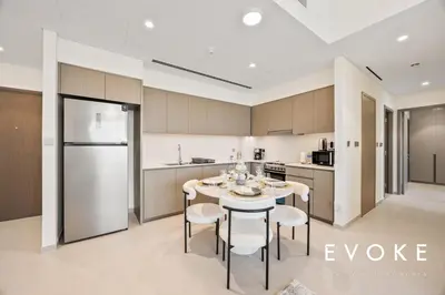 a kitchen with a table and chairs and a refrigerator at Grande 2BR Balcony Burj & Fountain Views by Evoke in Dubai