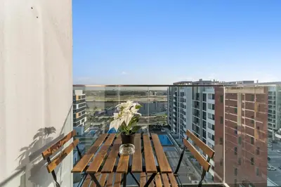 a wooden table on a balcony with a vase of flowers at Charming 1-Bedroom Close to Downtown in Dubai