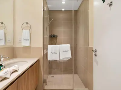 a bathroom with a shower and a sink with towels at Dubai Hills Retreat Garden, Pool & Park Access in Dubai