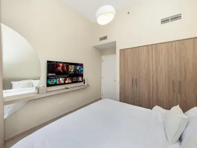 a white bedroom with a bed and a flat screen tv at Dubai Hills Retreat Garden, Pool & Park Access in Dubai