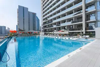 a large swimming pool with chairs and a building at Vogue Downtown Mag 318 near Burj Khalifa and Dubai Mall, Studio Apartment with Balcony, Canal and City Skyline View, Access to all Amenities in Dubai