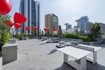 a park with benches and umbrellas in a city at Vogue Downtown Mag 318 near Burj Khalifa and Dubai Mall, Studio Apartment with Balcony, Canal and City Skyline View, Access to all Amenities in Dubai