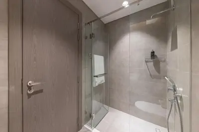 a bathroom with a shower and a glass door at Designer 3BR Lagoon Views Gym District One in Dubai