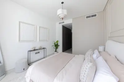 a white bedroom with a large bed with white walls at Designer 3BR Lagoon Views Gym District One in Dubai