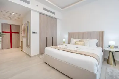 a white bedroom with a large white bed and a table at Chic Studio at ME DO RE Tower Stunning Views in Dubai