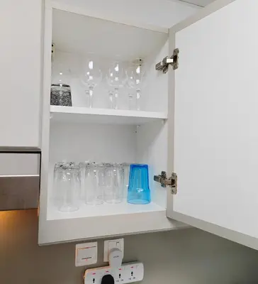 a cupboard filled with wine glasses in a kitchen at Luxury Studio Apartment in the beautiful Dubai in Dubai