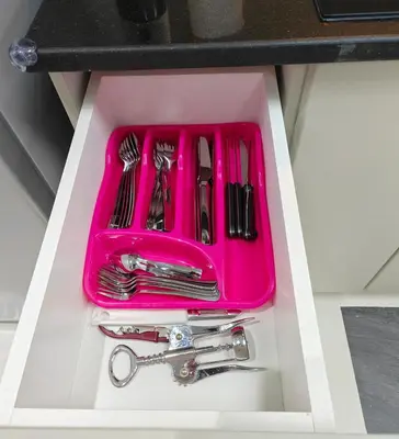a pink tray filled with utensils in a drawer at Luxury Studio Apartment in the beautiful Dubai in Dubai