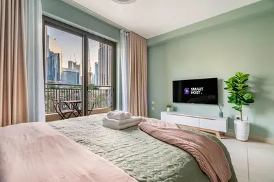 a bedroom with a bed and a large window at Modern Downtown Studio with Balcony & Parking in Dubai