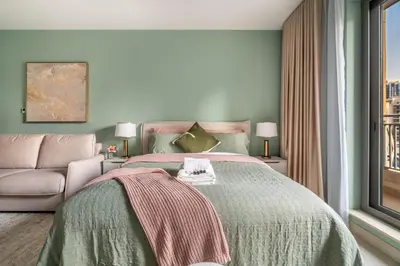 a bedroom with a bed and a couch and a window at Modern Downtown Studio with Balcony & Parking in Dubai