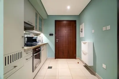 a kitchen with a brown door and a white and green wall at Modern Downtown Studio with Balcony & Parking in Dubai
