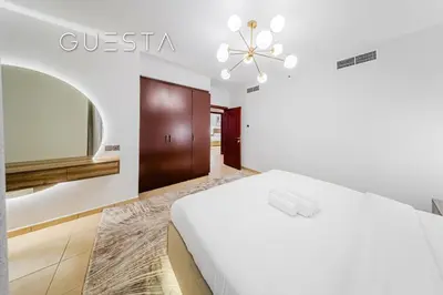 a white bedroom with a bed and a mirror at Jumeirah Beach Residence - Murjan 5, Dubai Marina in Dubai