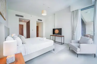 a white bedroom with a bed and a chair at Elegant 2 M with Direct Canal & Iconic View in Dubai