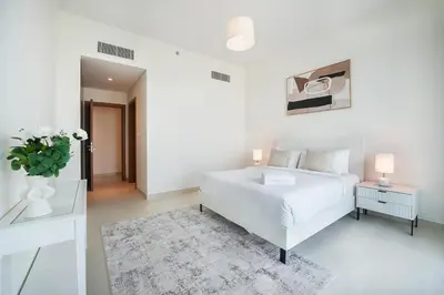 a white bedroom with a bed and a vase of flowers at Elegant 2 M with Direct Canal & Iconic View in Dubai