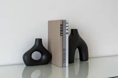 two black vases sitting next to a book at Luxury 2BR with Panoramic Sea View Private Beach in Dubai