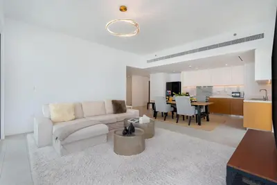 a living room with a white couch and a kitchen at Luxury 2BR with Panoramic Sea View Private Beach in Dubai