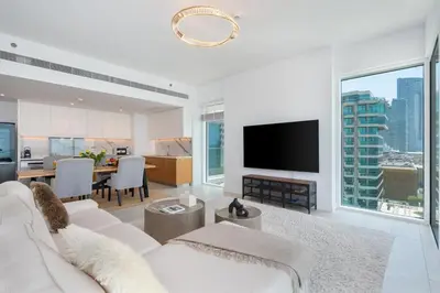 a living room with a white couch and a flat screen tv at Luxury 2BR with Panoramic Sea View Private Beach in Dubai