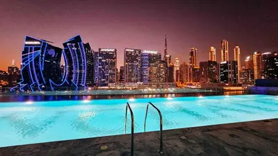 a swimming pool with a city skyline at night at Burj Khalifa View-Beautiful Pool-Gym-Business Bay in Dubai