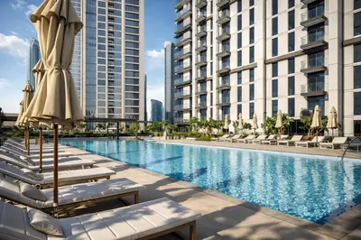 a swimming pool with lounge chairs and umbrellas next to tall buildings at BURJ CROWN - Elegant & Spacious Two-Bedroom Apartment in Downtown Dubai, Just 10 Minutes' Walk from Dubai Mall & Dubai Fountains, Surrounded by Iconic Landmarks in Dubai