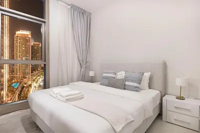 a bedroom with a large white bed with a window at BURJ CROWN - Elegant & Spacious Two-Bedroom Apartment in Downtown Dubai, Just 10 Minutes' Walk from Dubai Mall & Dubai Fountains, Surrounded by Iconic Landmarks in Dubai
