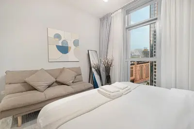 a white bedroom with a bed and a couch at BURJ CROWN - Elegant & Spacious Two-Bedroom Apartment in Downtown Dubai, Just 10 Minutes' Walk from Dubai Mall & Dubai Fountains, Surrounded by Iconic Landmarks in Dubai