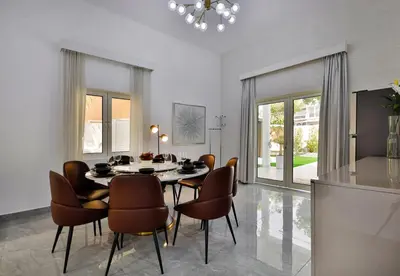 a dining room with a table and chairs at 5BR & Maids Room with Private Pool in The Aldea, The Villa - Allsopp & Allsopp in Dubai