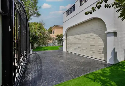 a garage with a gate and a driveway at 5BR & Maids Room with Private Pool in The Aldea, The Villa - Allsopp & Allsopp in Dubai