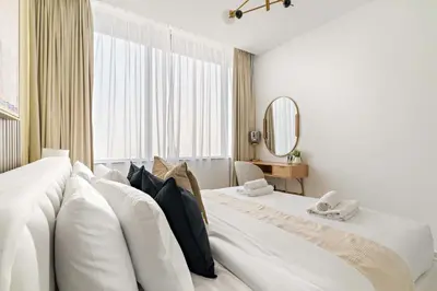 a white bedroom with two beds and a mirror at Silkhaus Comfy 1BDR at Sky Gardens in DIFC-NEW in Dubai