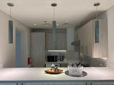 a kitchen with a white counter top and wooden cabinets at Spacious 1 bed with seaview in Seven Palm - Palm Jumeirah - IQPRO Holidays in Dubai