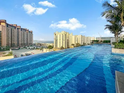 a large swimming pool with blue water in a city at NEW Luxury studio - Amazing Palm Views in Dubai