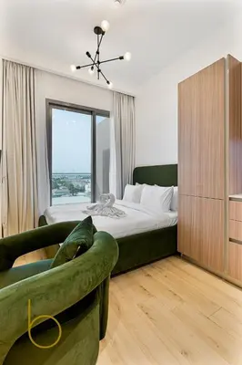 a bedroom with a bed and a green couch at Bookable - Studio Room, Bali Residences JVT in Dubai