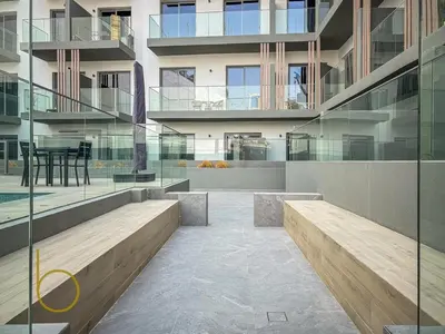 a building with glass walls and a patio with a table at Bookable - Studio Room, Bali Residences JVT in Dubai