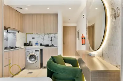 a kitchen with a washing machine and a green chair at Bookable - Studio Room, Bali Residences JVT in Dubai