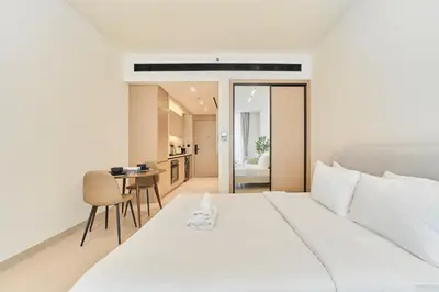 a bedroom with a large white bed and a table at Chic Studio in Dawn by Binghatti, Heart of JVC in Dubai