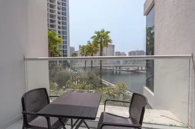 a balcony with a table and chairs and a view of a river at Chic Canal-ViewStudio by Czechin Pool & Gym Access in Dubai