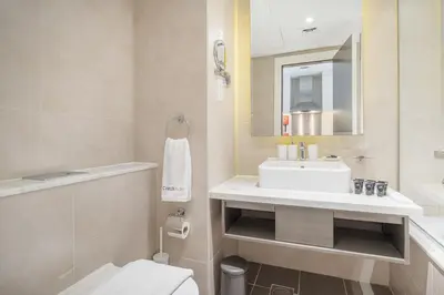 a bathroom with a sink and a toilet and a mirror at Chic Canal-ViewStudio by Czechin Pool & Gym Access in Dubai