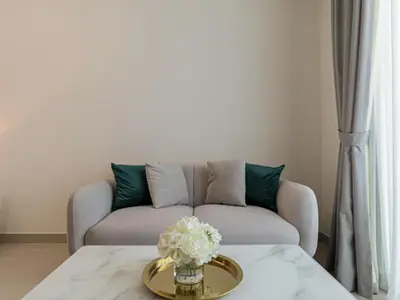 a living room with a couch and a table with flowers at Welhome - Modern Gold Accents Studio in JVC with Balcony in Dubai
