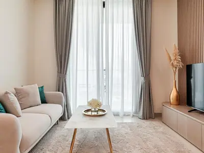 a living room with a couch and a tv at Welhome - Modern Gold Accents Studio in JVC with Balcony in Dubai