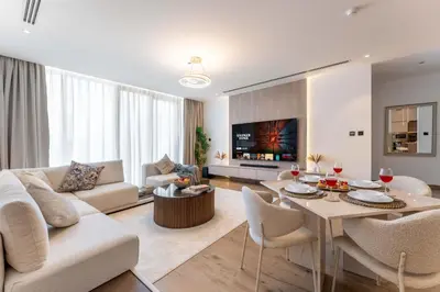 a living room with a couch and a table and chairs at 2BDR with Pool, Sauna and PS5 - Near Circle Mall in Dubai