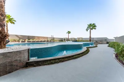 a swimming pool in a resort with palm trees at 2BDR with Pool, Sauna and PS5 - Near Circle Mall in Dubai