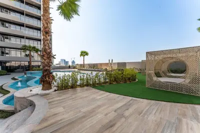 a courtyard with a pool and palm trees and a building at 2BDR with Pool, Sauna and PS5 - Near Circle Mall in Dubai